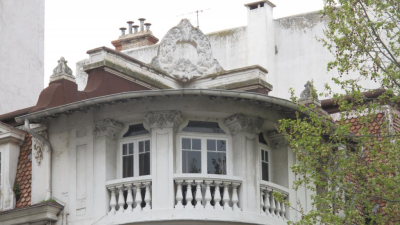  Angle du dernier niveau traité en courbe : 3 fenetres , balcons a balustres, sur le toit une couronne de branches de pin 