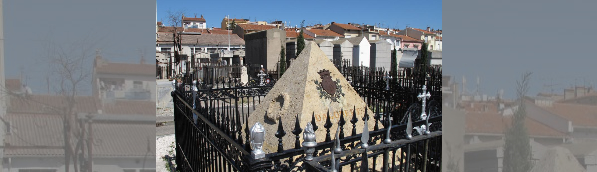 Tomeau en forme de pyramide entourée d'une grille, le blason de Dagobert:2 licornes et un lion séparé par un V pointe en haut.