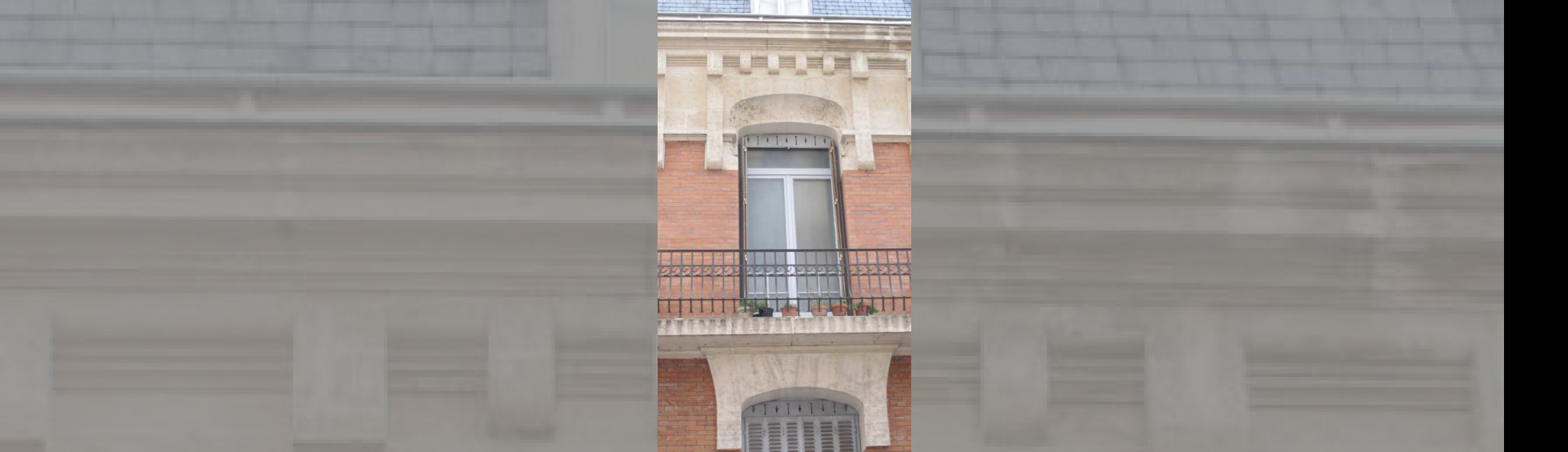 Mélange de matériaux autour d'une baie :linteau en pierre, mur en briques, garde corps en fer forgé.