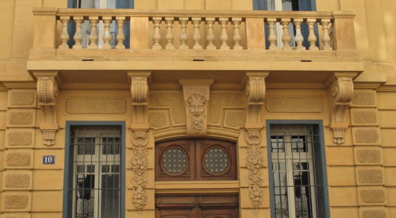 Façade peinte en ocre jaune ,balcon à balustres au 1er,guirlandes et tête de faune ornant les piedroits et linteau de l'entrée